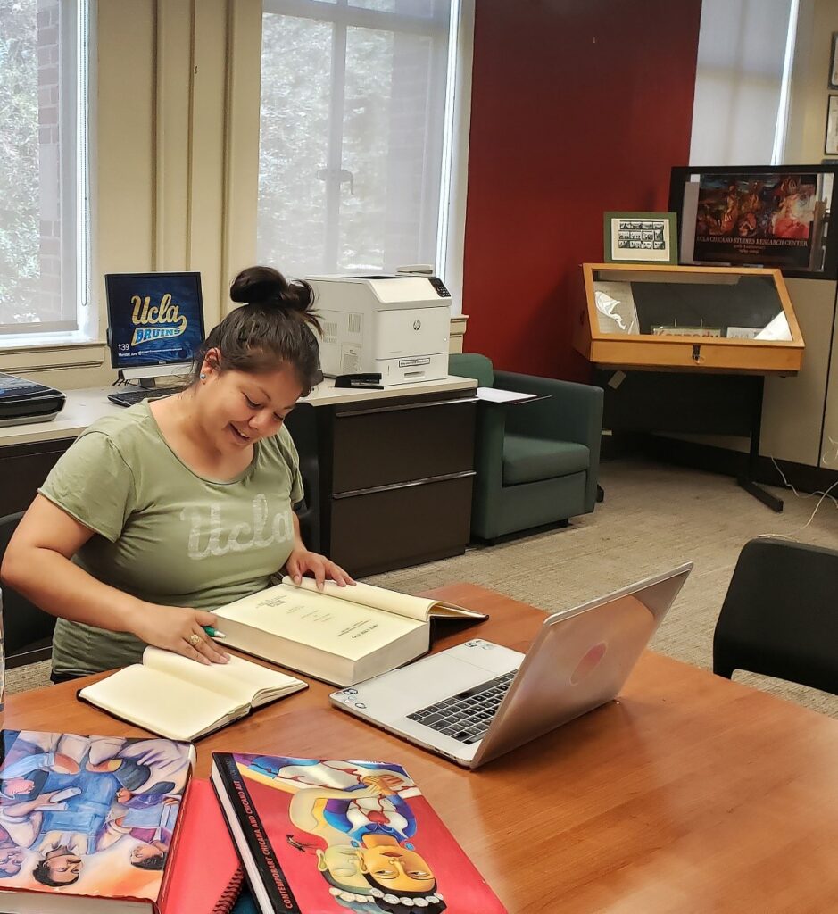 Photo of Gabriela Rodriguez-Gomez sitting at a table with books and a laptop while conducting research at the CSRC.