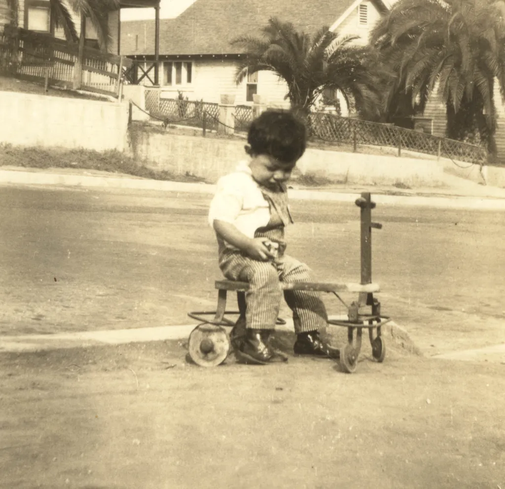 Black and white photo of Ignacio Serna as a young child sitting on a tricycle in the early 1930s.