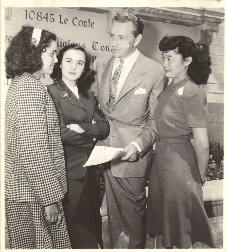 Black and white photo of actor Paul Henreid talking with three members of the Panel of Americans in 1945.