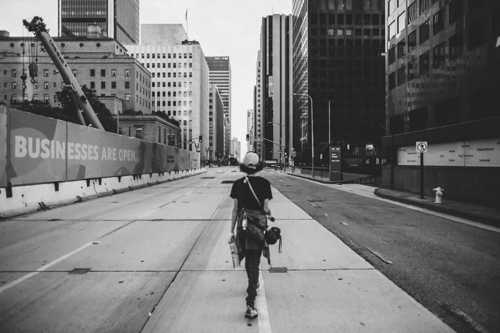Black and white photograph of Carmen Argote walking alone down the middle of a wide street in Los Angeles.