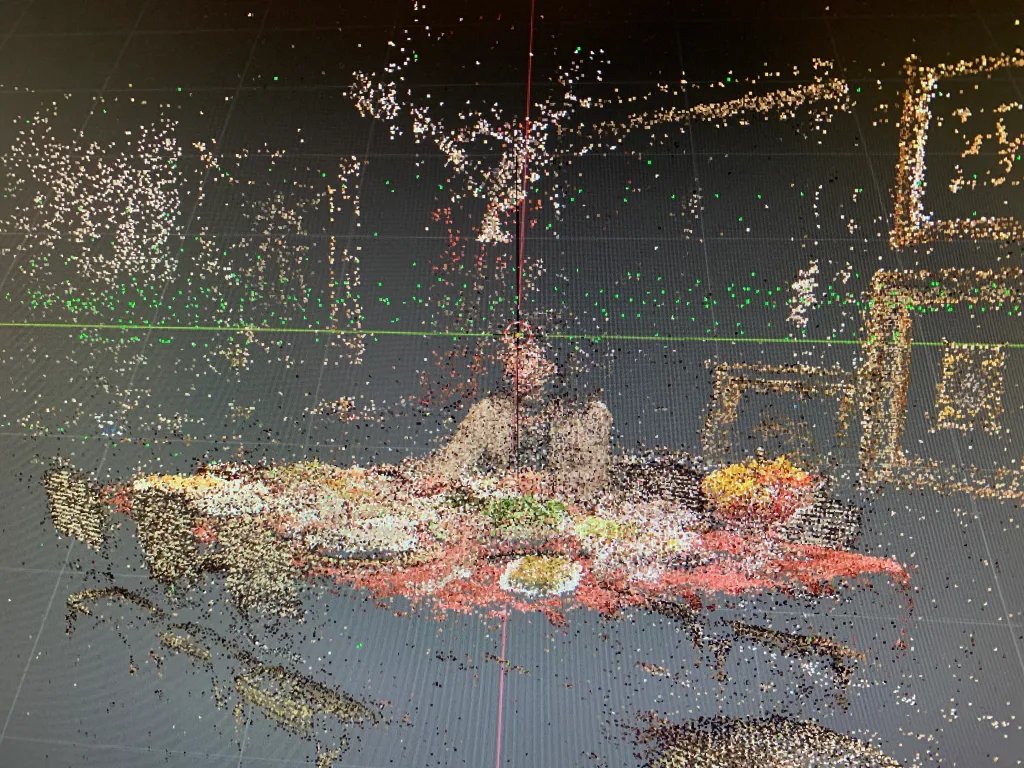 Digital point cloud from Zeynep Abes's film Mama showing a dining table and room formed by multicolored points.