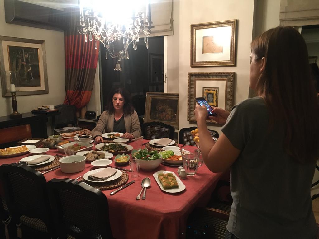 Photograph of Zeynep Abes's film Mama showing two women in a dining room with a table that has food and dishes.