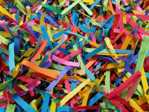 Close-up photo showing a large pile of colorful strips of shredded paper in red, blue, yellow, green, and pink.