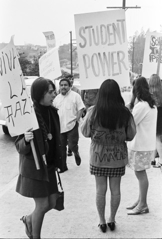 Black and white historical photo of students and supporters holding protest signs, including a large “Student Power” sign, during the 1968 walkouts.